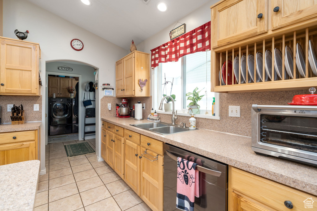 Kitchen featuring stainless steel dishwasher, light brown cabinetry, a sink, washer / clothes dryer, and light countertops