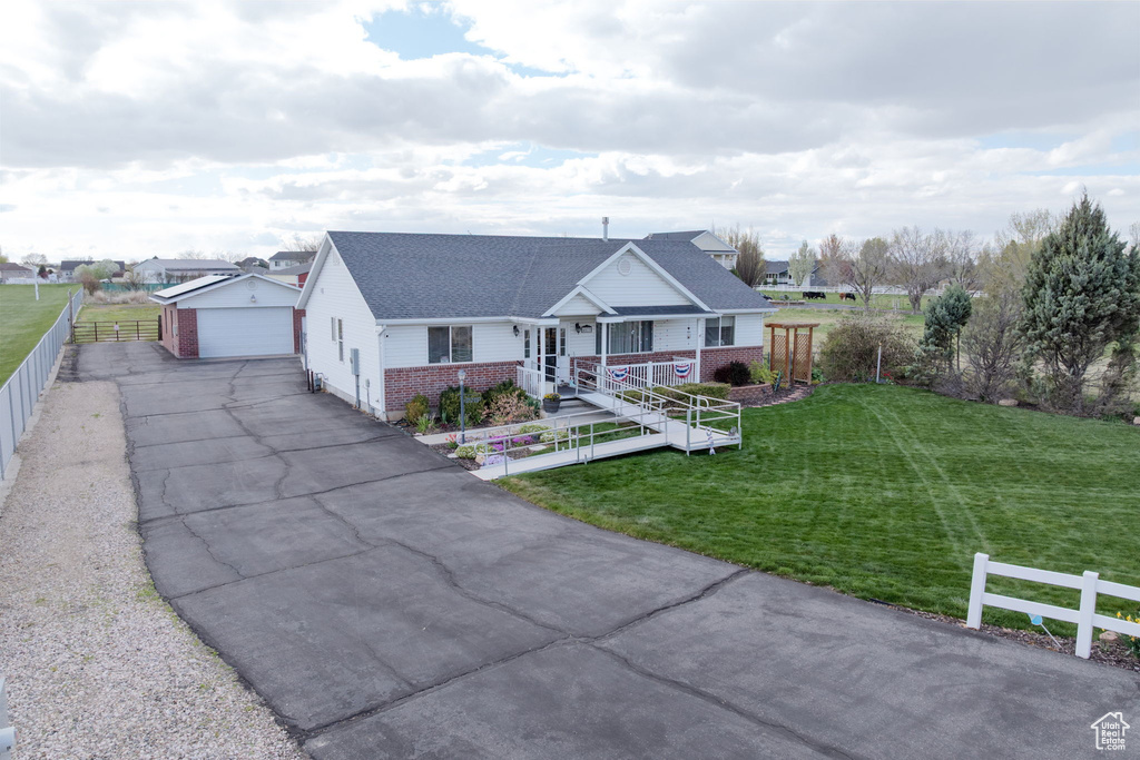View of front facade featuring brick siding, a front yard, a garage, and fence