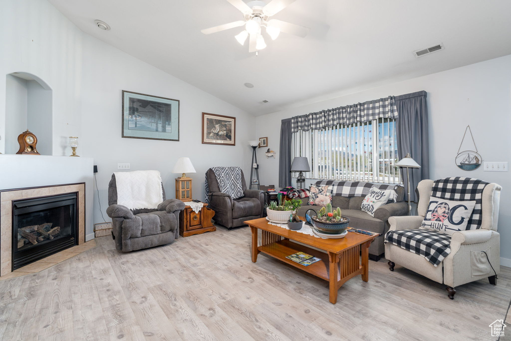 Living room with wood finished floors, visible vents, lofted ceiling, and ceiling fan
