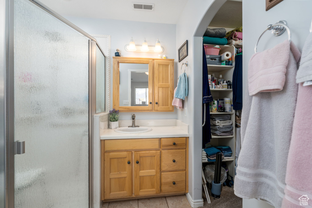 Bathroom with tile patterned floors, a stall shower, visible vents, a spacious closet, and vanity