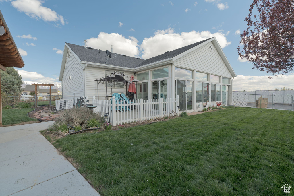Rear view of house with a lawn, a fenced backyard, a sunroom, and roof with shingles