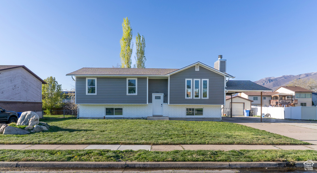 Raised ranch with fence, a chimney, concrete driveway, and a garage