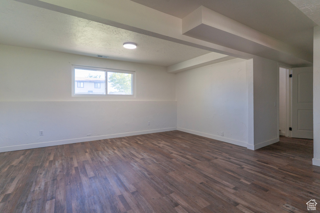 Empty room featuring baseboards, a textured ceiling, and dark wood-style flooring