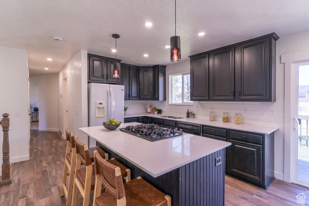 Kitchen with a breakfast bar, black appliances, wood finished floors, and light countertops