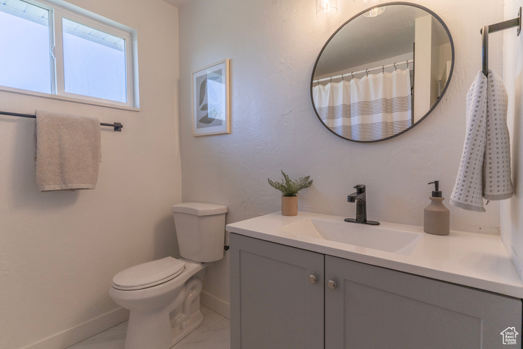 Bathroom featuring toilet, vanity, and baseboards