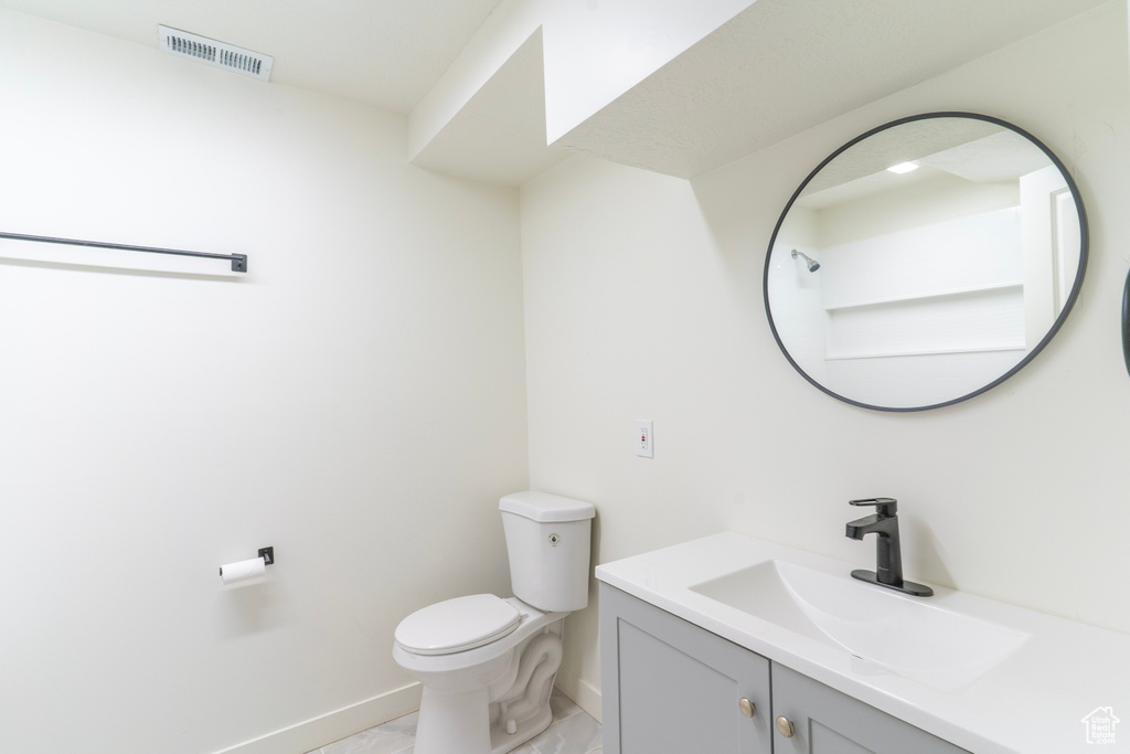 Bathroom featuring visible vents, toilet, vanity, and baseboards