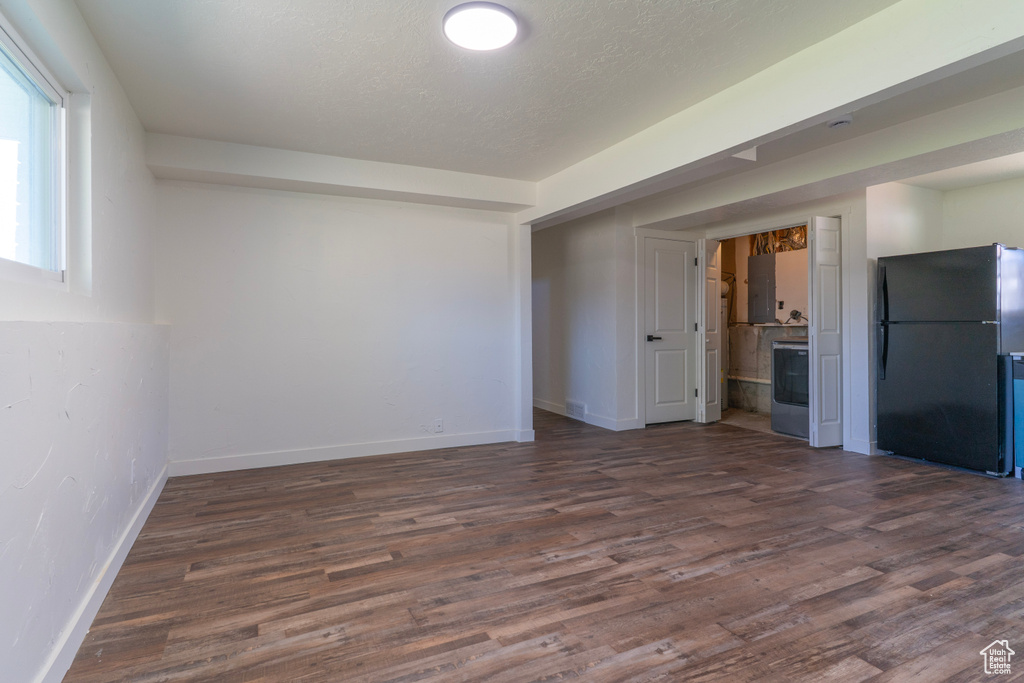 Spare room with a textured ceiling, washer / clothes dryer, dark wood-style floors, and baseboards