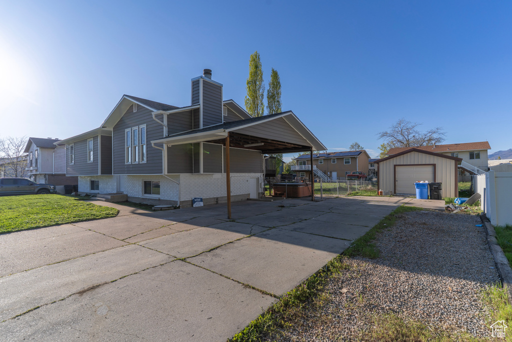 View of front of house with a chimney, fence, driveway, an outdoor structure, and a garage