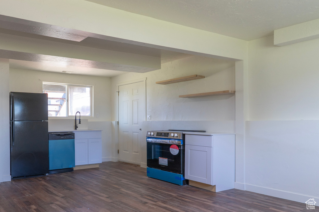 Kitchen with freestanding refrigerator, electric range, dishwasher, a sink, and dark wood-style floors