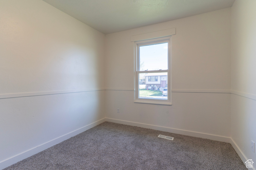 Carpeted spare room featuring baseboards, visible vents, and a wealth of natural light