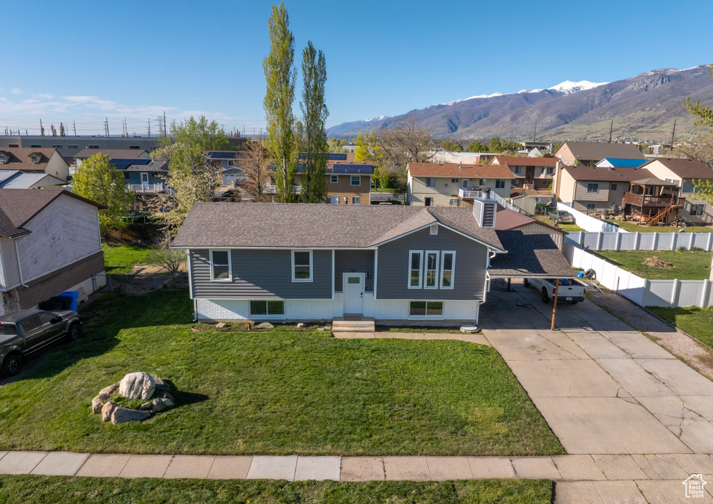 View of front facade featuring fence, a residential view, a mountain view, a front lawn, and concrete driveway