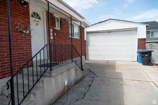 Property entrance featuring brick siding, driveway, and a garage