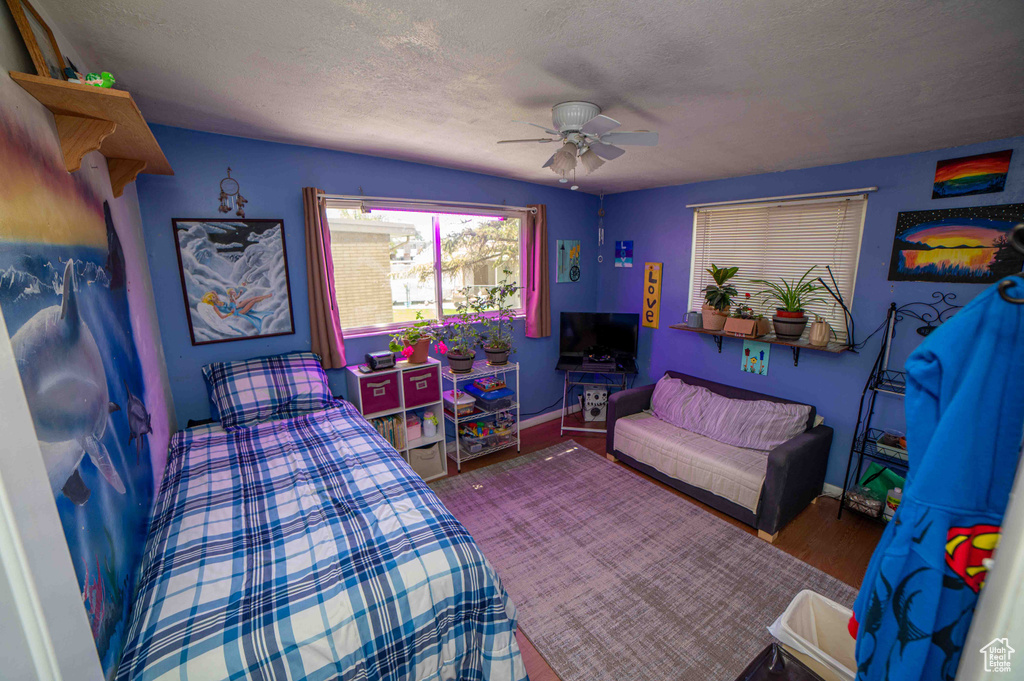 Bedroom featuring baseboards, a ceiling fan, a textured ceiling, and wood finished floors