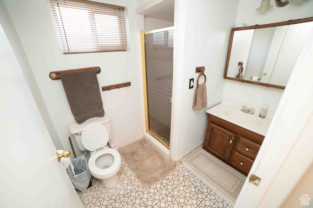 Bathroom featuring vanity, tile patterned floors, a stall shower, and toilet