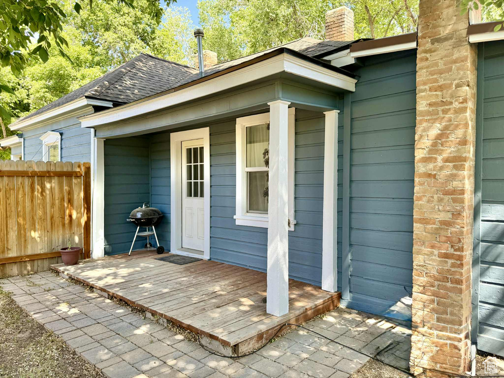 Property entrance featuring a shingled roof and a chimney
