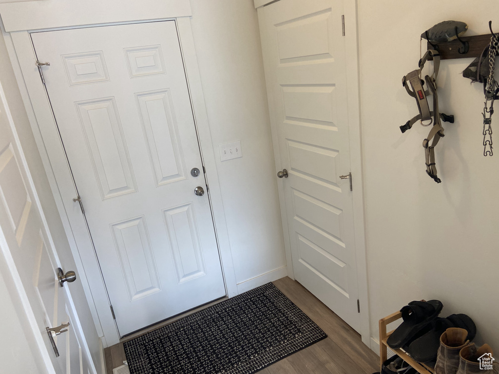 Doorway to outside with dark wood-type flooring and baseboards
