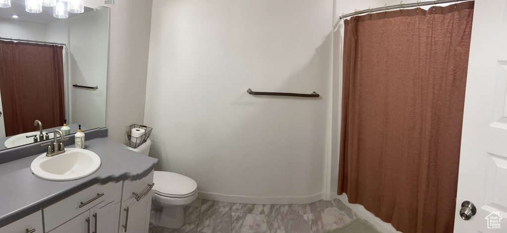 Full bathroom with marble finish floor, toilet, and vanity