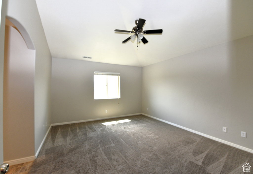 Spare room with arched walkways, carpet floors, ceiling fan, and vaulted ceiling