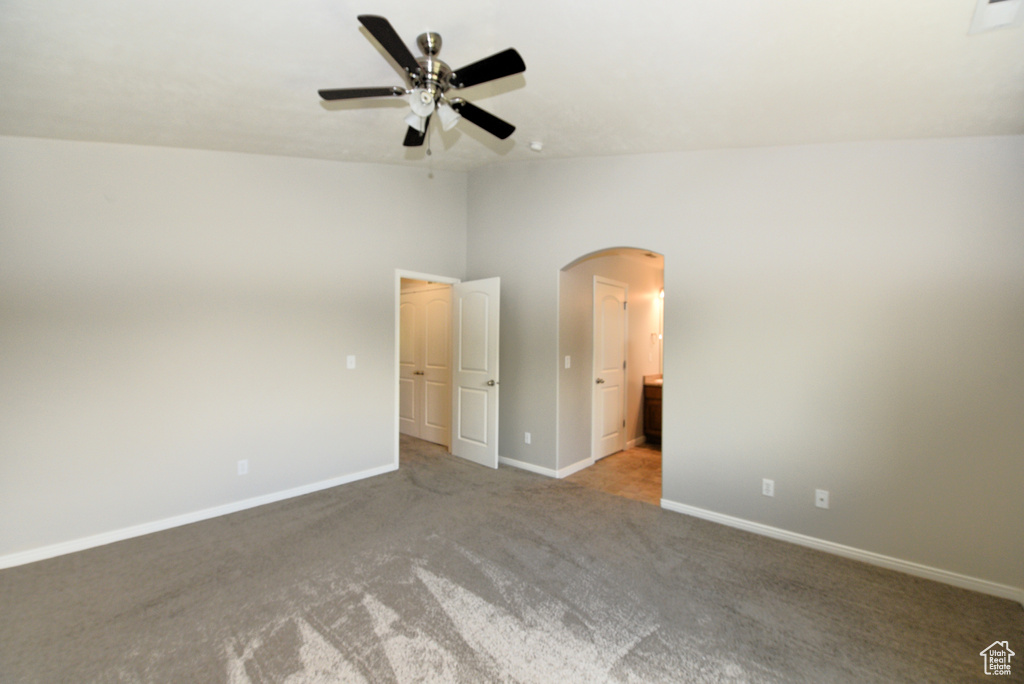Unfurnished bedroom with arched walkways, carpet floors, lofted ceiling, and a ceiling fan