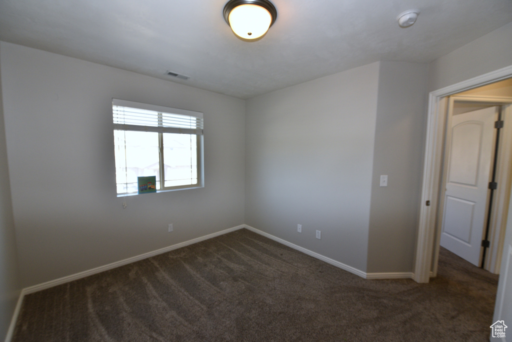 Carpeted spare room featuring baseboards and a smoke detector