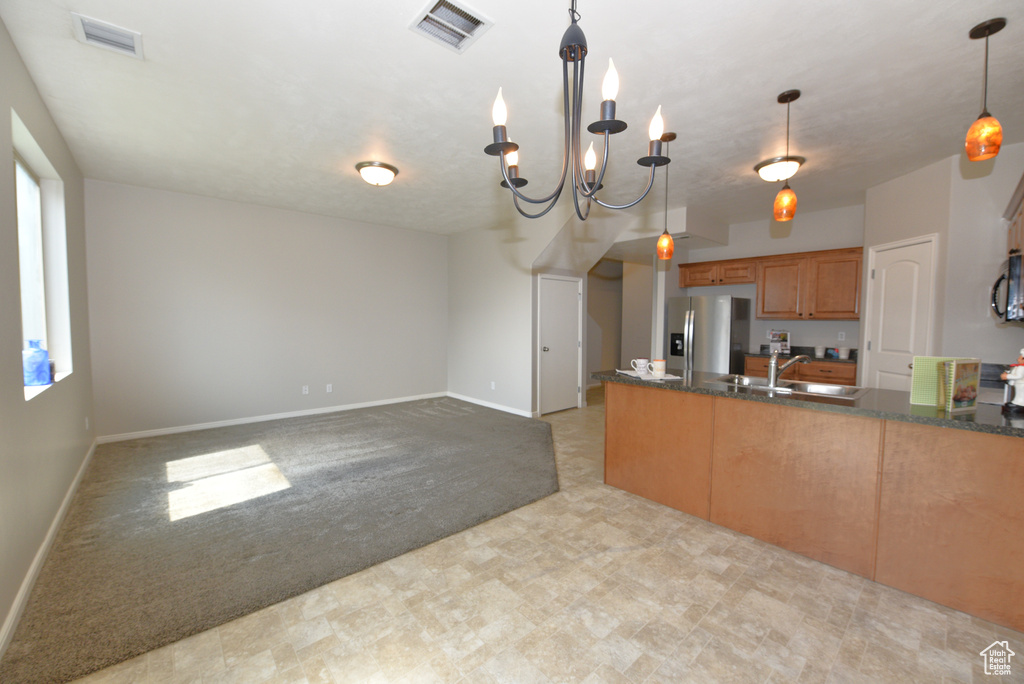 Kitchen featuring stainless steel refrigerator with ice dispenser, dark countertops, a peninsula, and light carpet