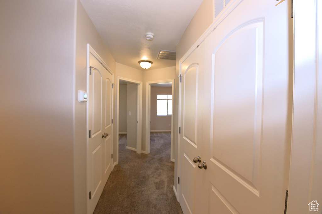 Hallway with dark colored carpet and baseboards