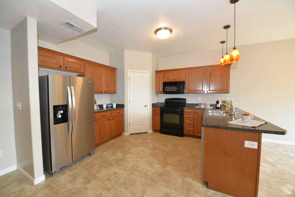 Kitchen with black appliances, a peninsula, dark countertops, brown cabinetry, and pendant lighting