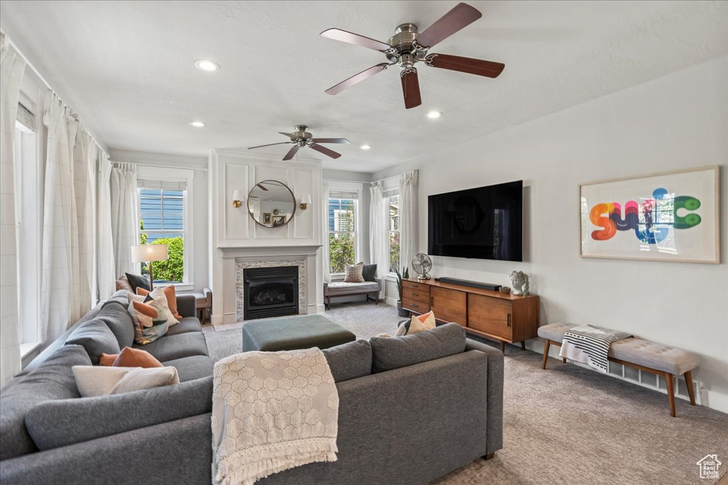 Carpeted living area featuring a fireplace, a ceiling fan, and recessed lighting