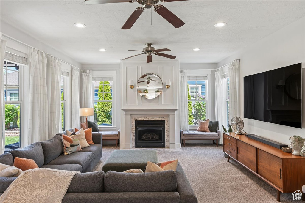 Living room with carpet, a fireplace, a wealth of natural light, and ceiling fan