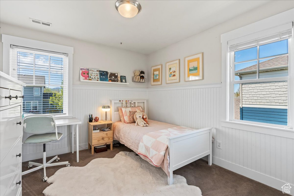 Bedroom with wainscoting, visible vents, and multiple windows
