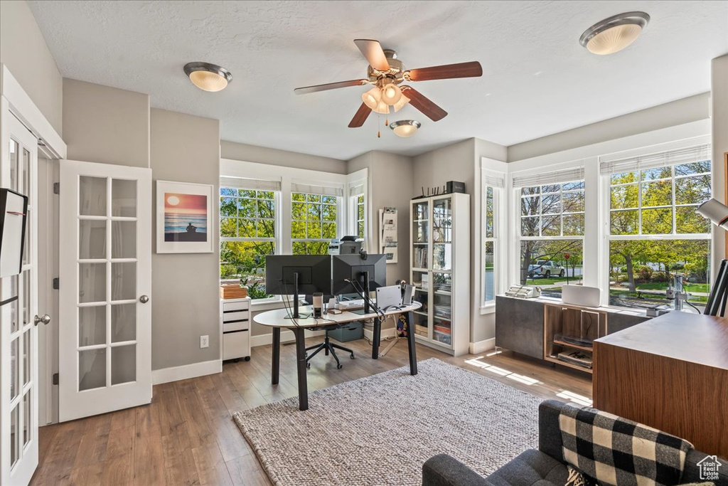 Office area with french doors, wood finished floors, a wealth of natural light, and ceiling fan
