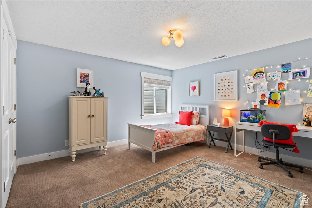 Carpeted bedroom featuring a textured ceiling, visible vents, and baseboards
