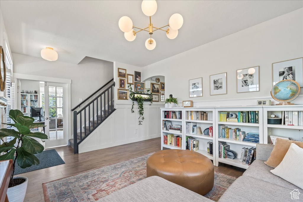 Living area with wainscoting, an inviting chandelier, wood finished floors, stairway, and a decorative wall