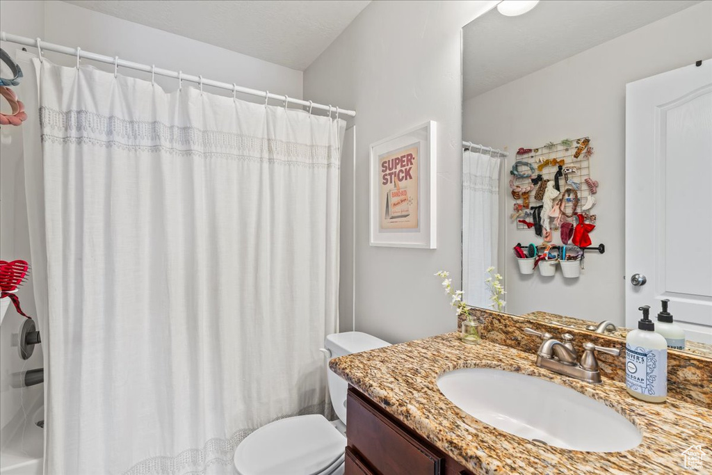 Bathroom featuring toilet, vanity, and a shower with shower curtain