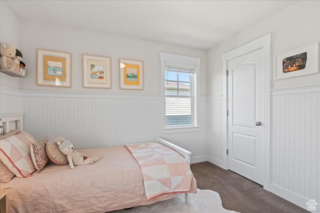 Bedroom featuring dark colored carpet and wainscoting