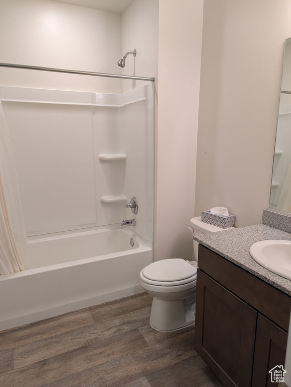 Bathroom with shower / tub combination, wood finished floors, toilet, and vanity
