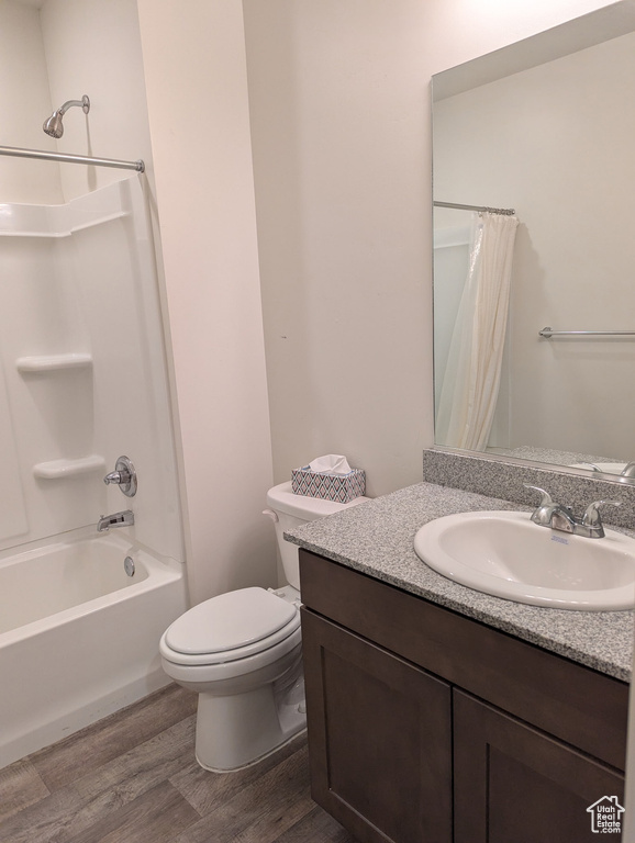 Bathroom with wood finished floors, toilet, shower / bathtub combination with curtain, and vanity