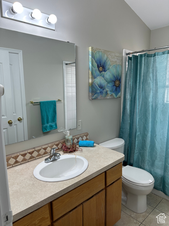 Bathroom featuring a shower with curtain, vanity, tile patterned flooring, and toilet