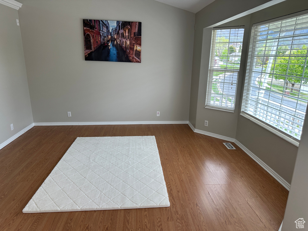 Unfurnished room with baseboards, wood finished floors, and visible vents