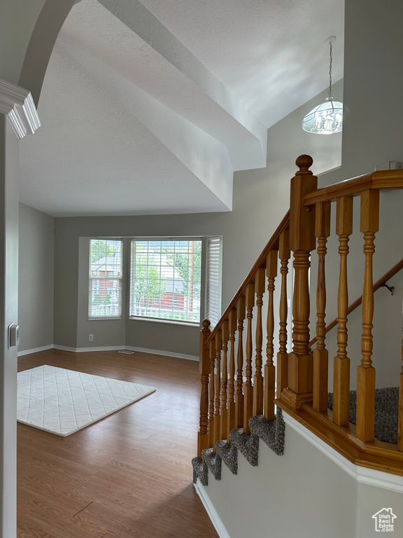 Stairway featuring arched walkways, wood finished floors, and baseboards