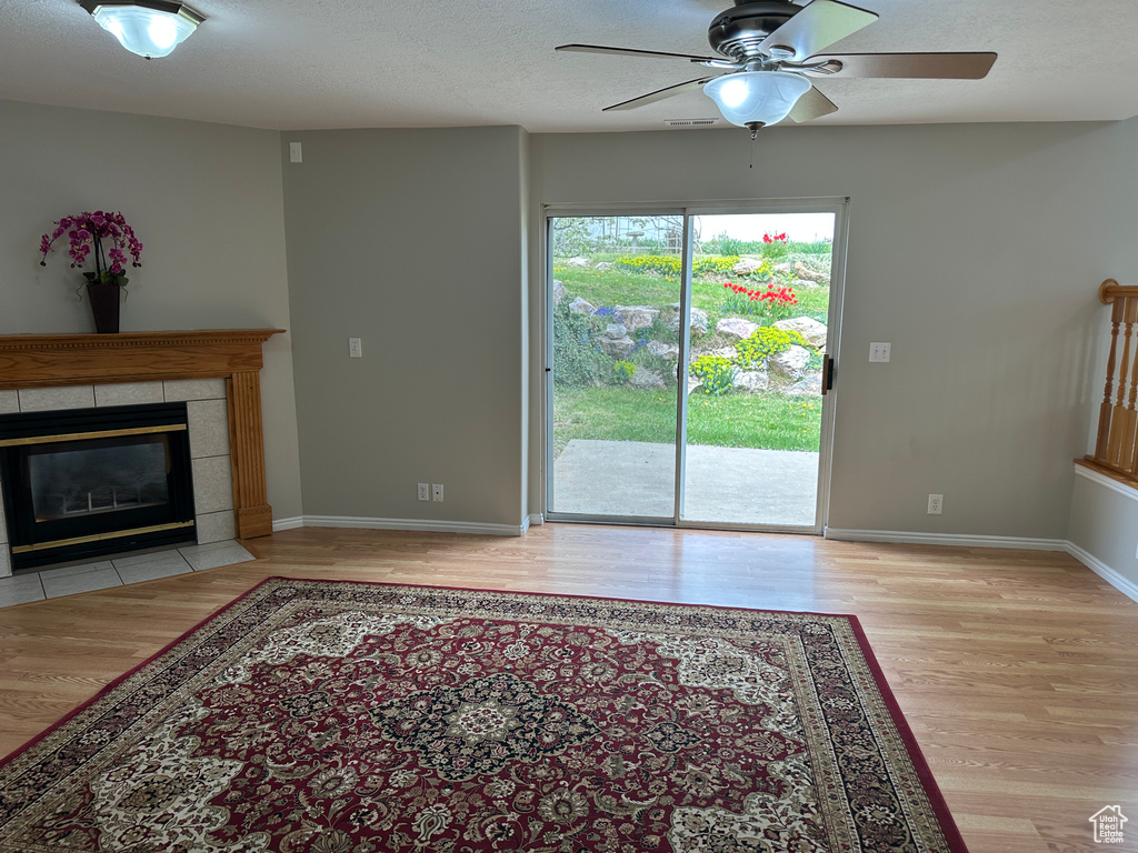 Unfurnished living room featuring baseboards, a ceiling fan, wood finished floors, and a fireplace