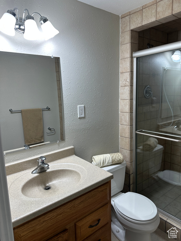 Full bathroom with a stall shower, a textured wall, vanity, and toilet