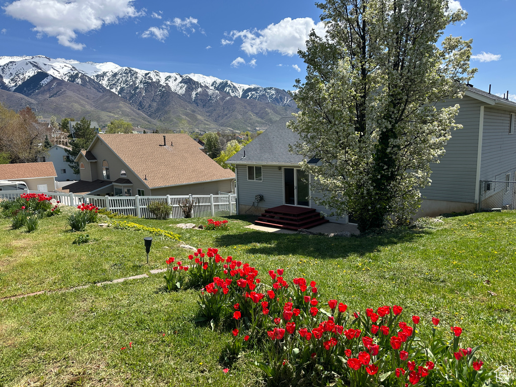 Back of property featuring a lawn, fence, and a mountain view