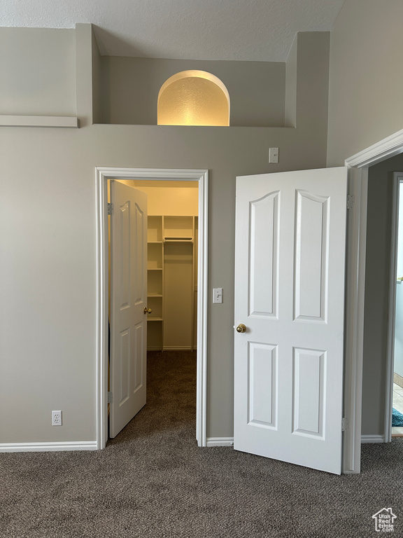 Unfurnished bedroom with baseboards, carpet flooring, a spacious closet, and a closet
