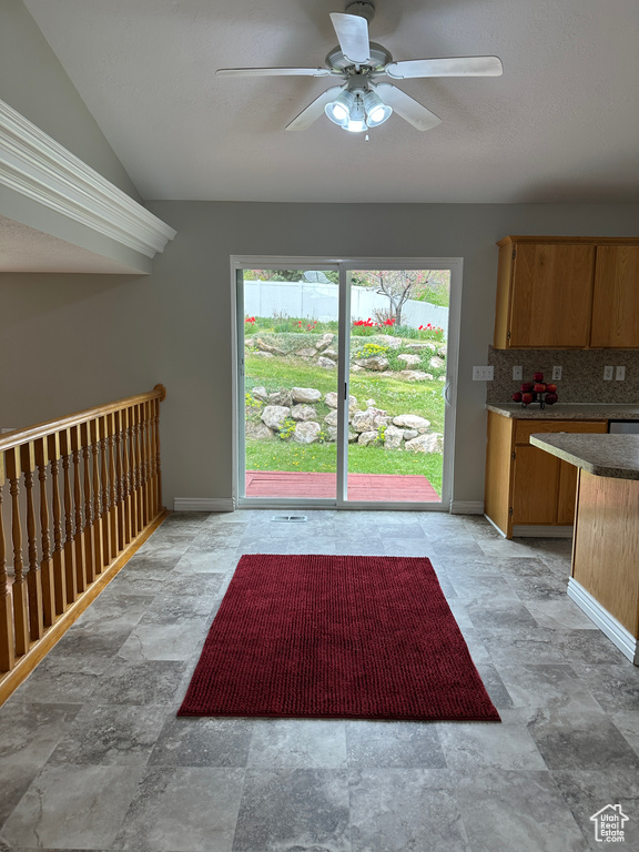 Interior space with stone finish floor, vaulted ceiling, baseboards, and ceiling fan