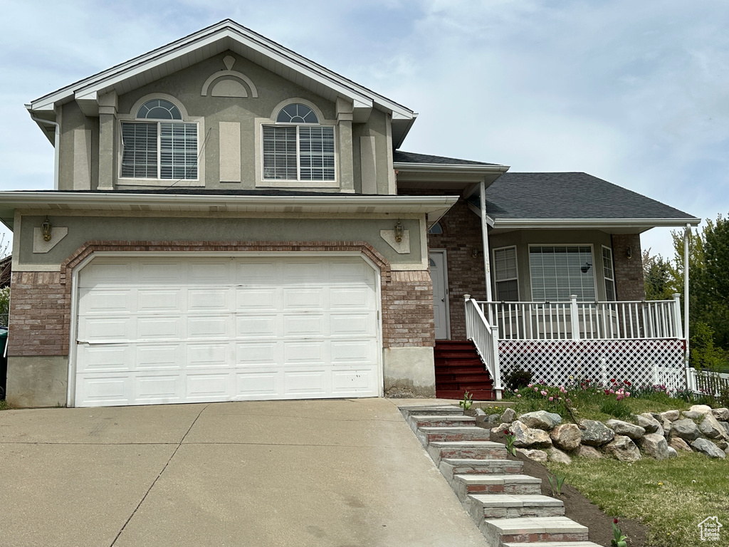 View of front of property with brick siding, covered porch, driveway, and a garage