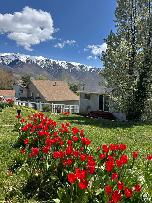 View of yard featuring a deck with mountain view and fence