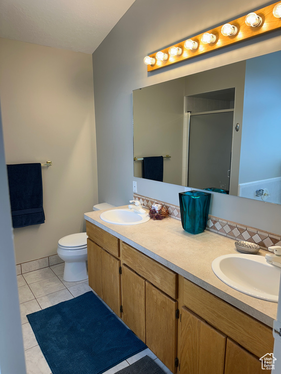 Bathroom featuring double vanity, toilet, a stall shower, and a sink