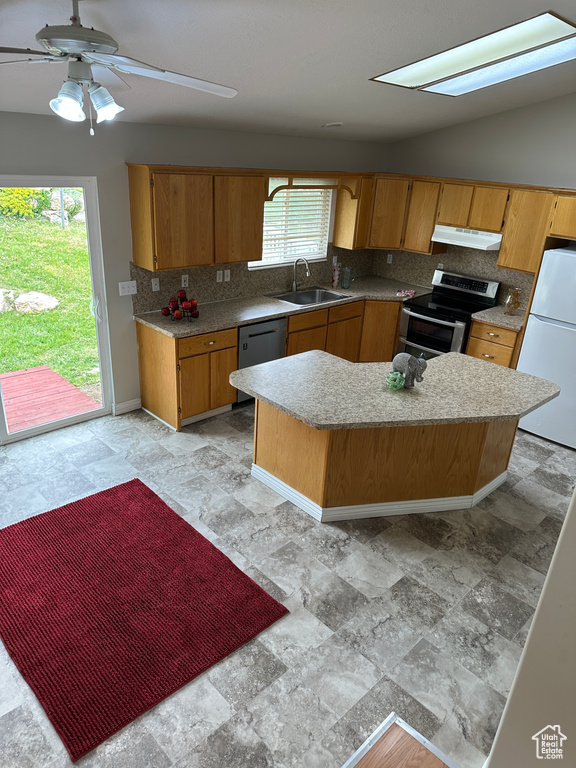 Kitchen with a sink, appliances with stainless steel finishes, light countertops, backsplash, and under cabinet range hood