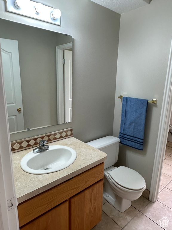 Bathroom with vanity, tile patterned flooring, a textured ceiling, and toilet